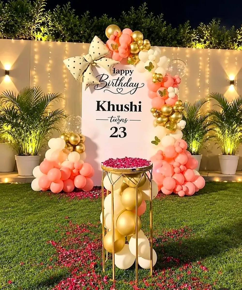 Pink, peach and gold balloon arch birthday decoration with fairy-light backdrop on a lawn by Mayur Events Bilaspur